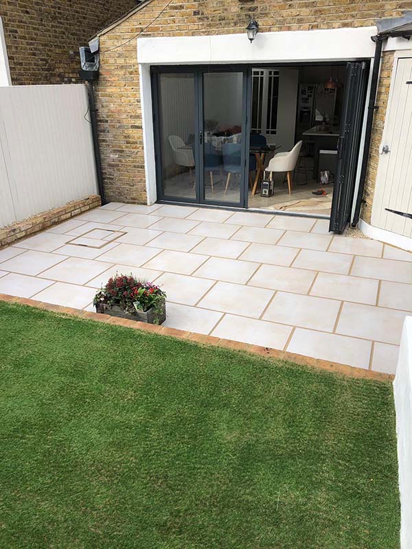 Porcelain patio with brick edging and lawn