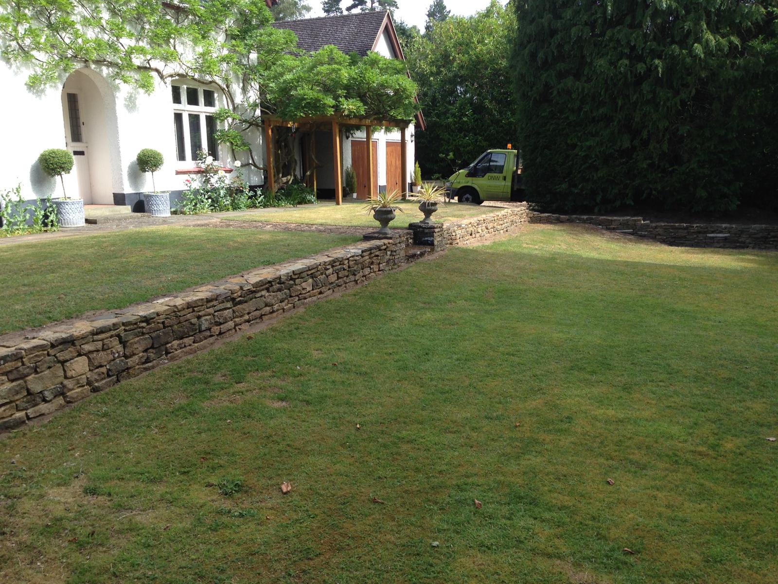 Dry stone retaining wall across a lawn