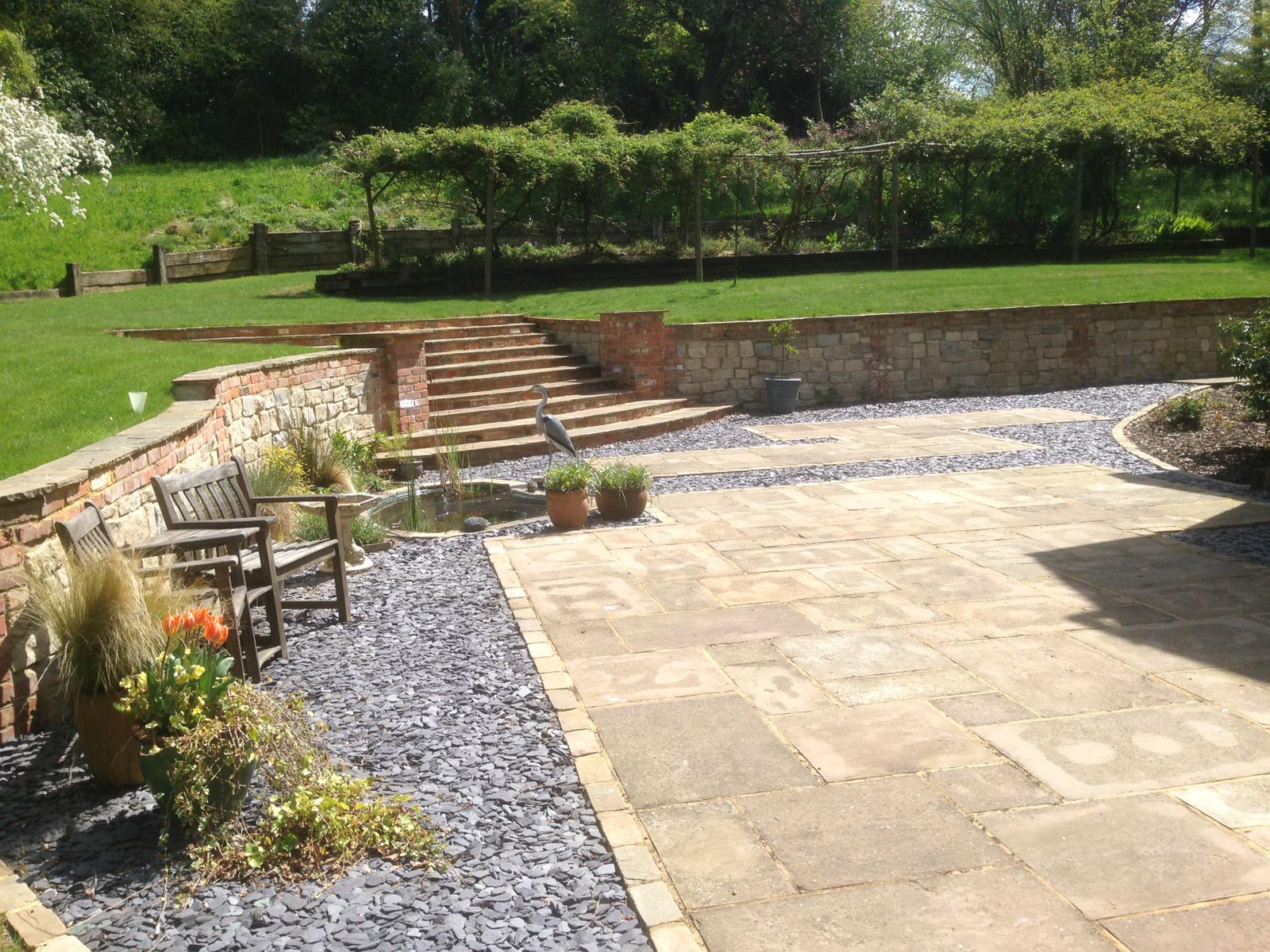 Terraced garden with sandstone paving, slate mulch, brick and stone retaining walls and steps
